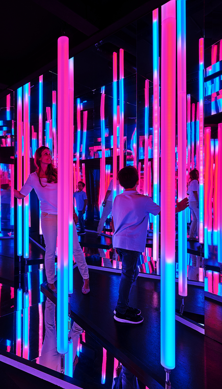 Eine Frau und ein Junge stehen in einem Leuchtenden Spiegellabyrinth.