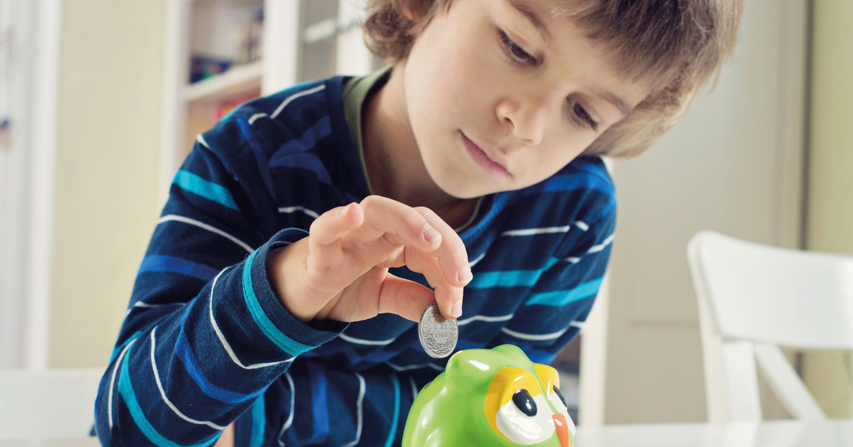 Ein Junge wirft eine 5 Franken Münze in ein «Kässeli».
