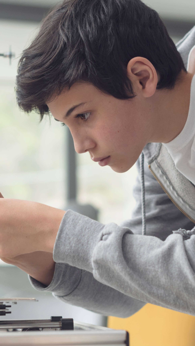 Junge, der einen 3D Drucker einstellt.