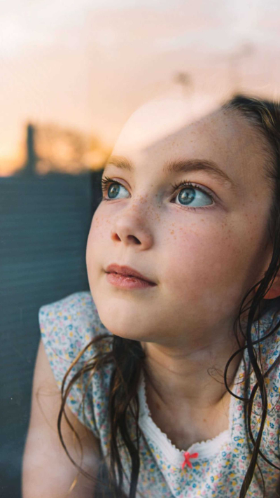 Mädchen, das am Abend aus dem Fenster den Mond beobachtet.