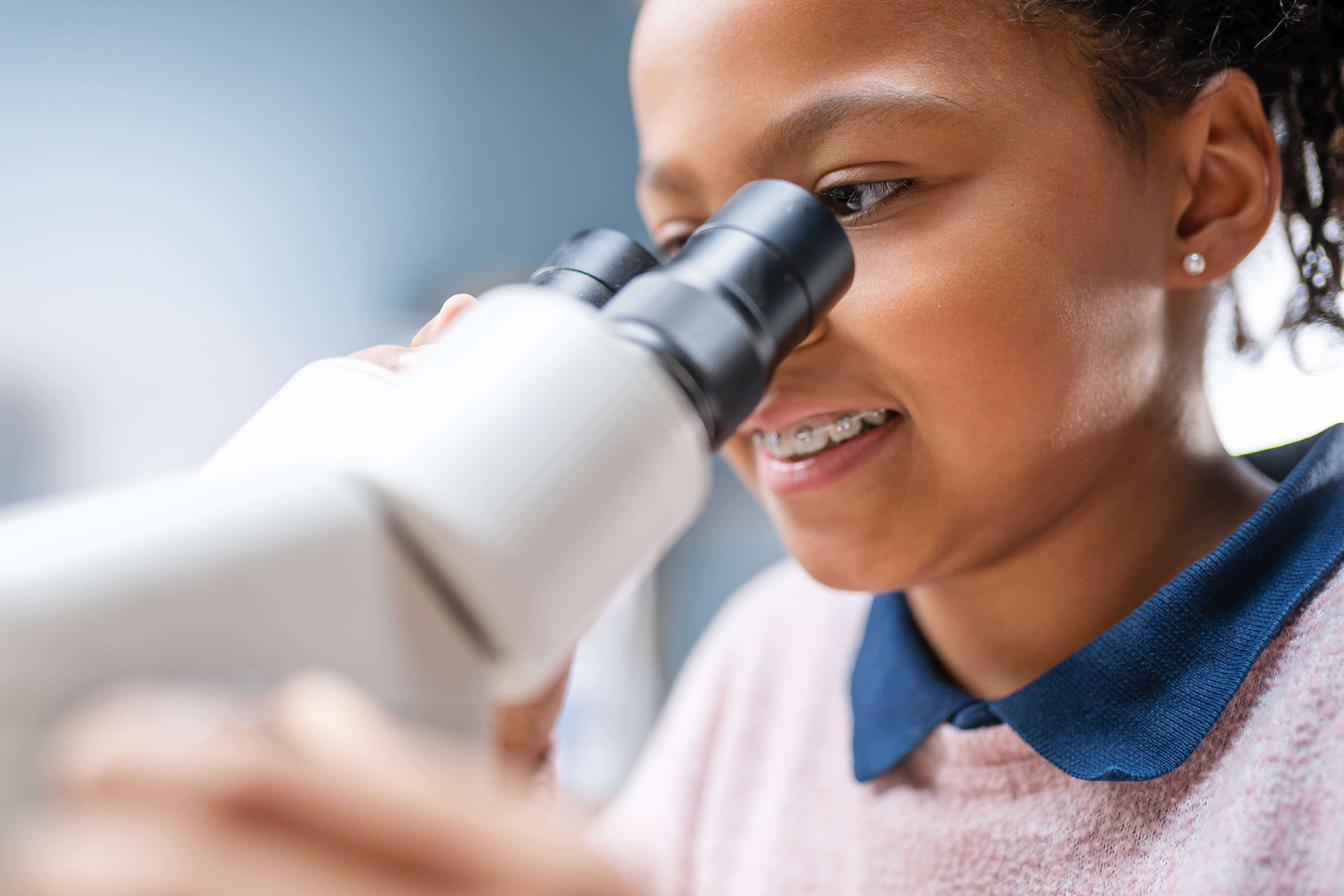 Mädchen, das etwas durch ein Mikroskop betrachtet.