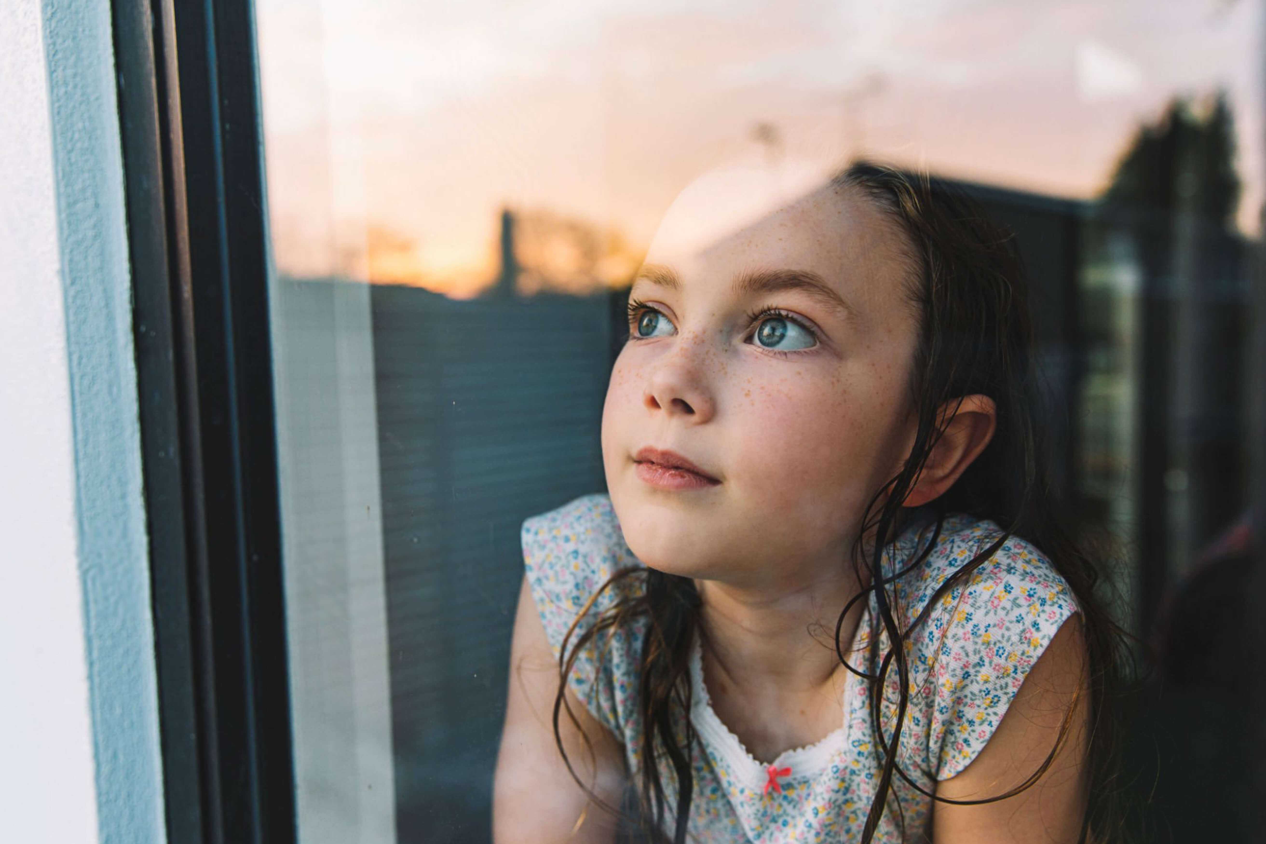 Mädchen, das am Abend aus dem Fenster den Mond beobachtet.