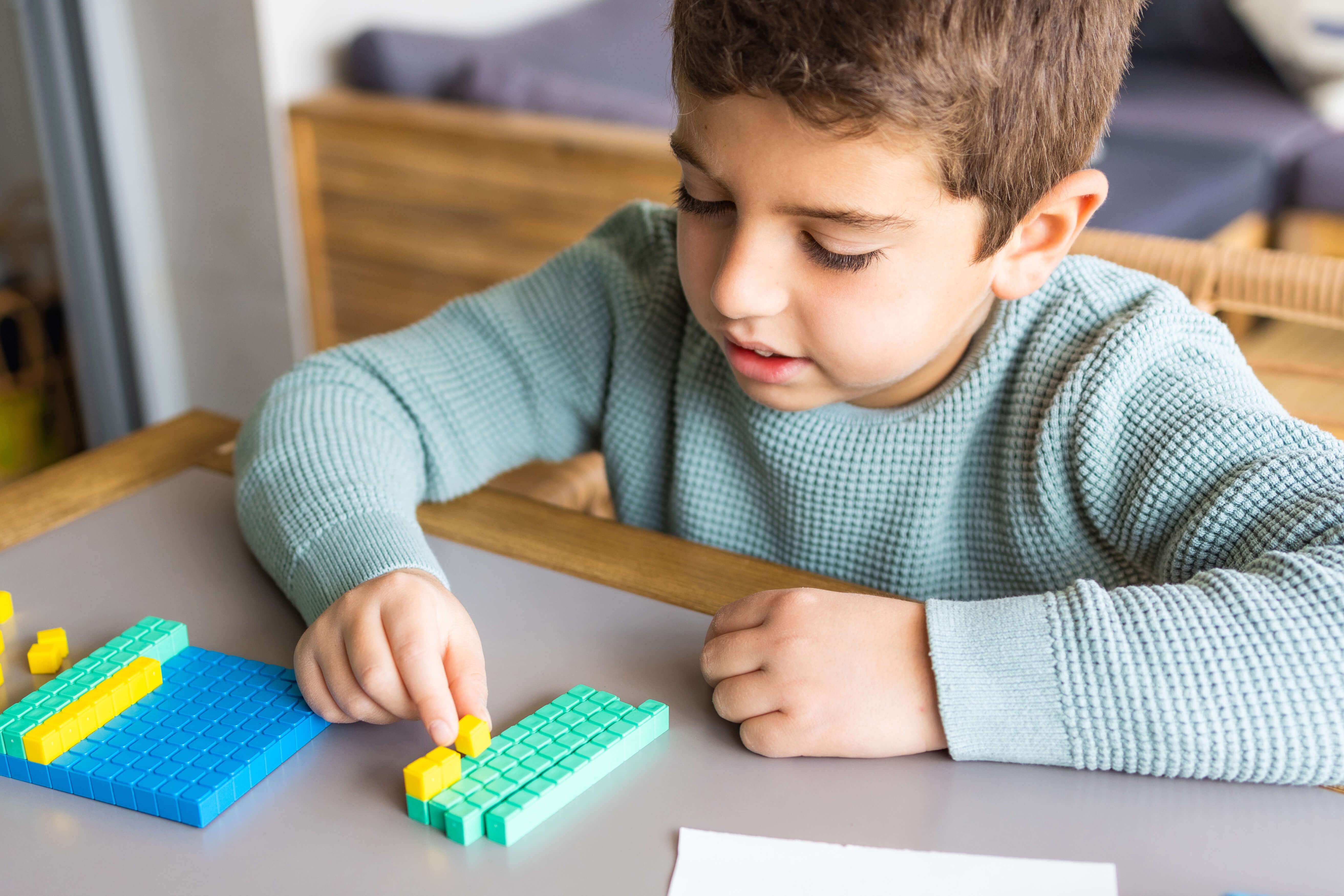 Bub mit 10-er System-Klötzen.