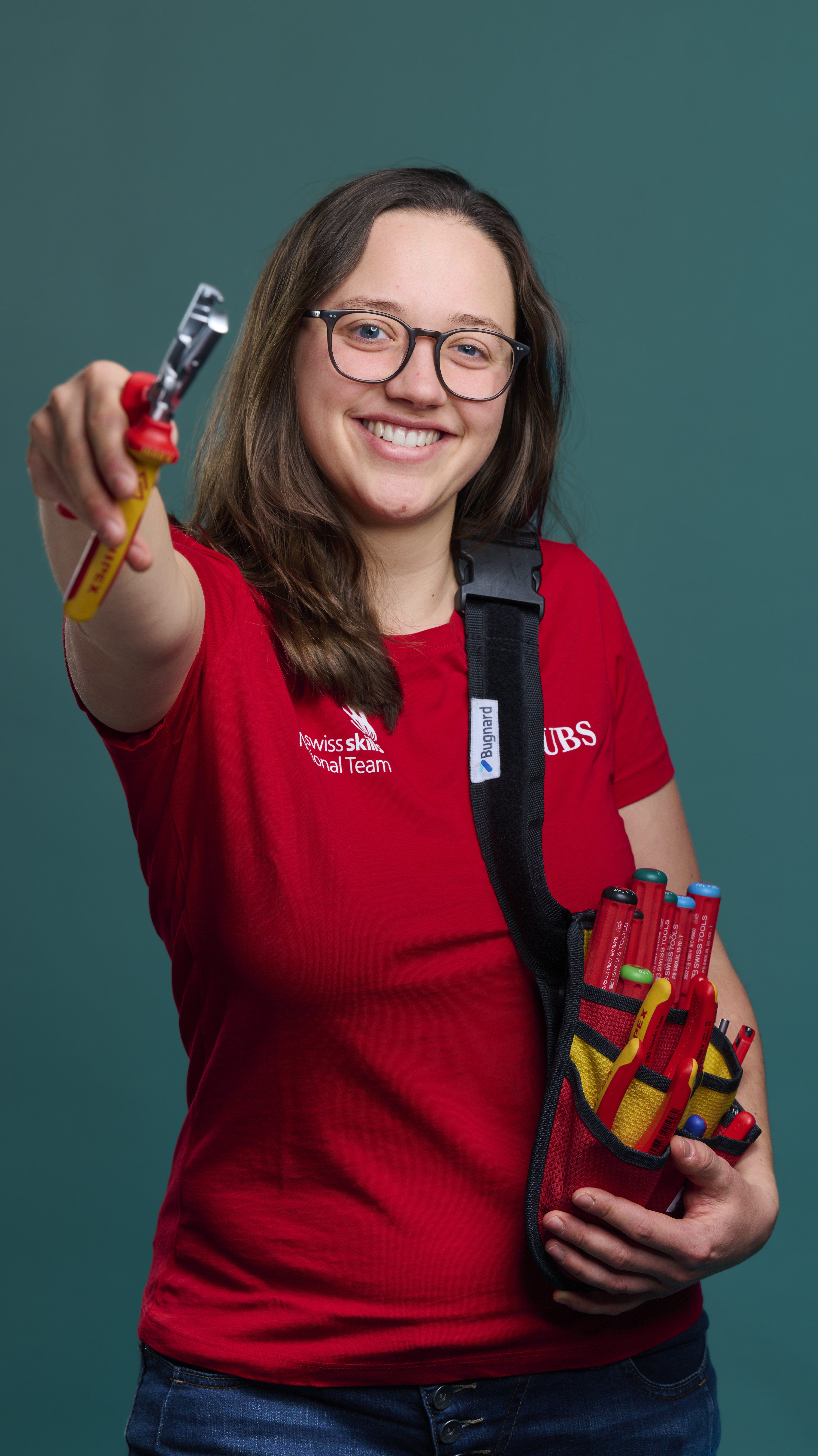 Jana im roten Swissskills Tshirt und ihren Schraubenschlüsseln und Zangen in den Händen.