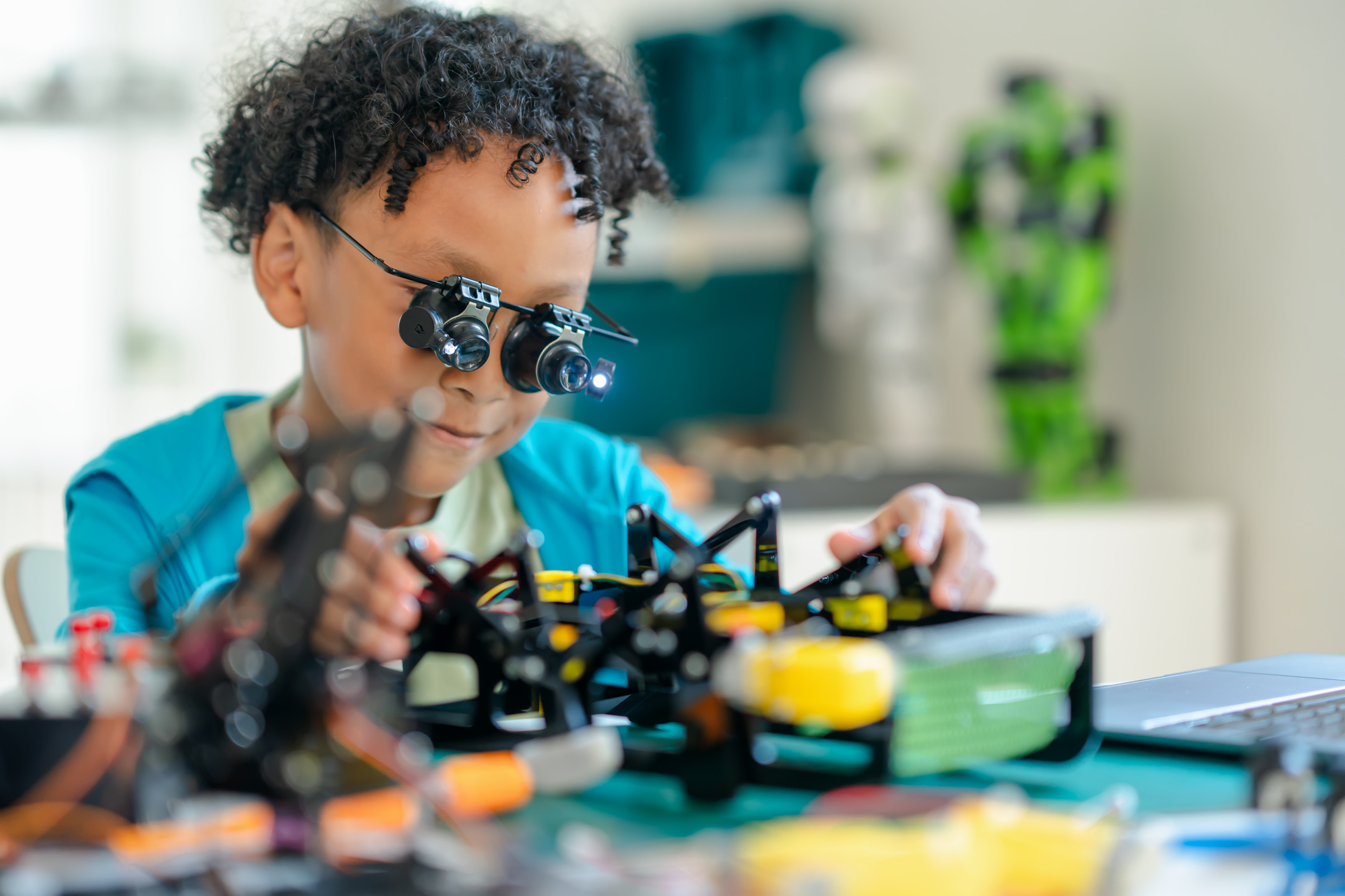 Junge, der mit Vergrösserungs-Brille einen Roboter baut.